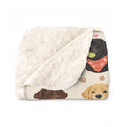 A folded Cream sherpa fleece blanket shows its fluffy cream back beside a black Lab holding a tennis ball on the printed front.