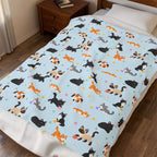 A Sky cat throw blanket in velveteen plush lies across a made bed beside a wooden nightstand, with cartoon cats and yarn balls.