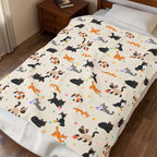 Viewed from above at an angle, a Cream velveteen plush blanket with cartoon cats covers a made bed beside a wooden nightstand.