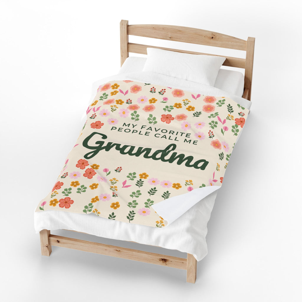 A bottom corner of a Cream velveteen plush blanket turns back on a small wooden bed, revealing the plain white back beside the floral front.