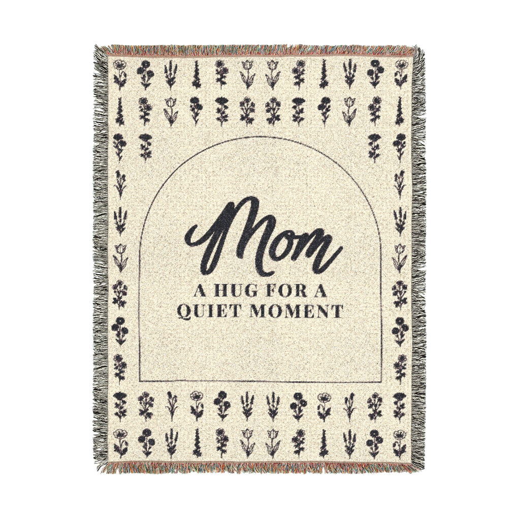 A tall Cream wildflower throw in woven cotton, 60 x 80 inches, lies on white with "Mom" inside a dark arch, even flower rows and fringe.