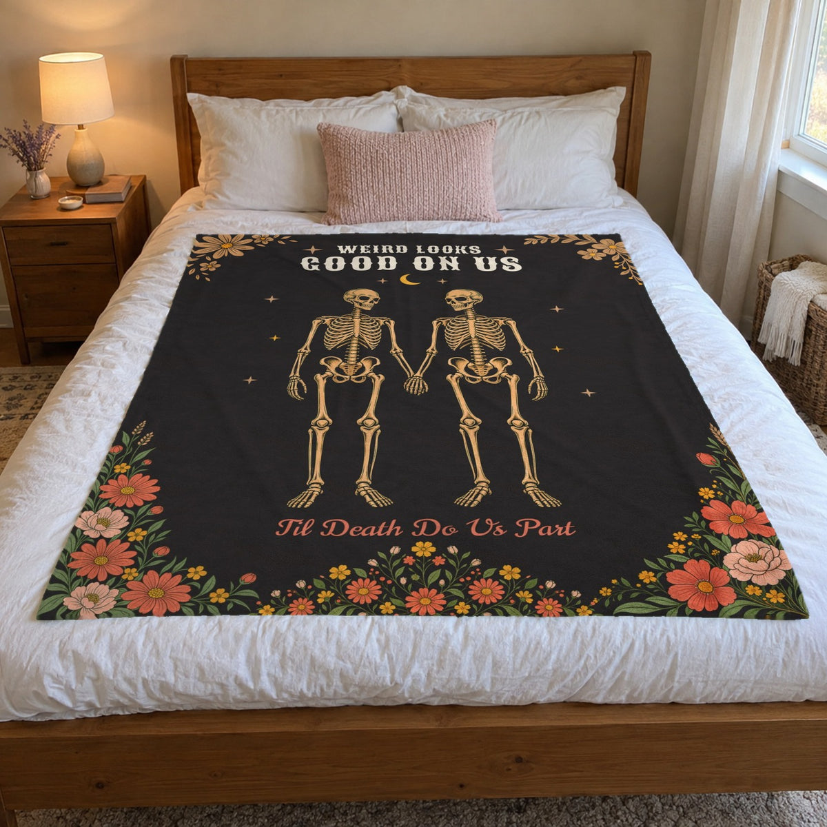 In a bright bedroom, a 50 x 60 inch Black velveteen plush blanket with tan skeletons and wildflowers lies on a white duvet.