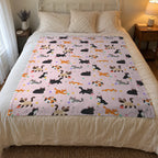 Morning light falls on a 50 x 60 inch Blush cat print blanket in velveteen plush on a guest room bed with a white iron frame.