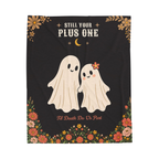 A Black velveteen plush blanket lies flat on white, with a ghost couple below "STILL YOUR / PLUS ONE" and wildflowers beneath.