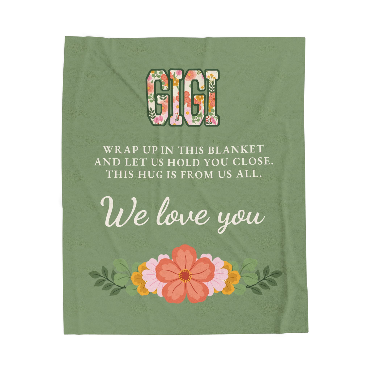 Floral "GIGI" letters top a Sage Gigi blanket in velveteen plush, laid flat on white with the cream message and garland in view.