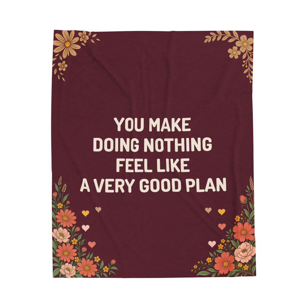Laid flat on white, the Wine velveteen plush blanket reads "You make doing nothing feel like a very good plan" above wildflowers and small hearts.
