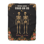 Two tan skeletons hold hands on a Black sherpa fleece blanket laid flat on white, with cream capitals and rounded corners.