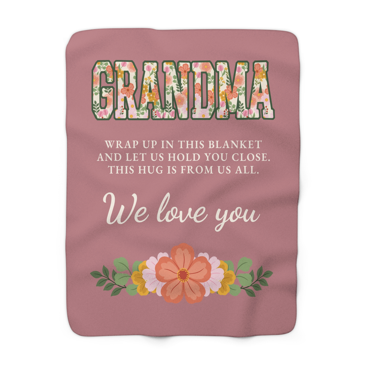 Laid flat on white, a Dusty rose grandma hug blanket in sherpa fleece shows floral letters and "THIS HUG IS FROM US ALL."