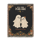 Two cream ghosts, one with a flower on her head, appear on a Black woven cotton blanket laid flat on white, with fringe on all four sides.