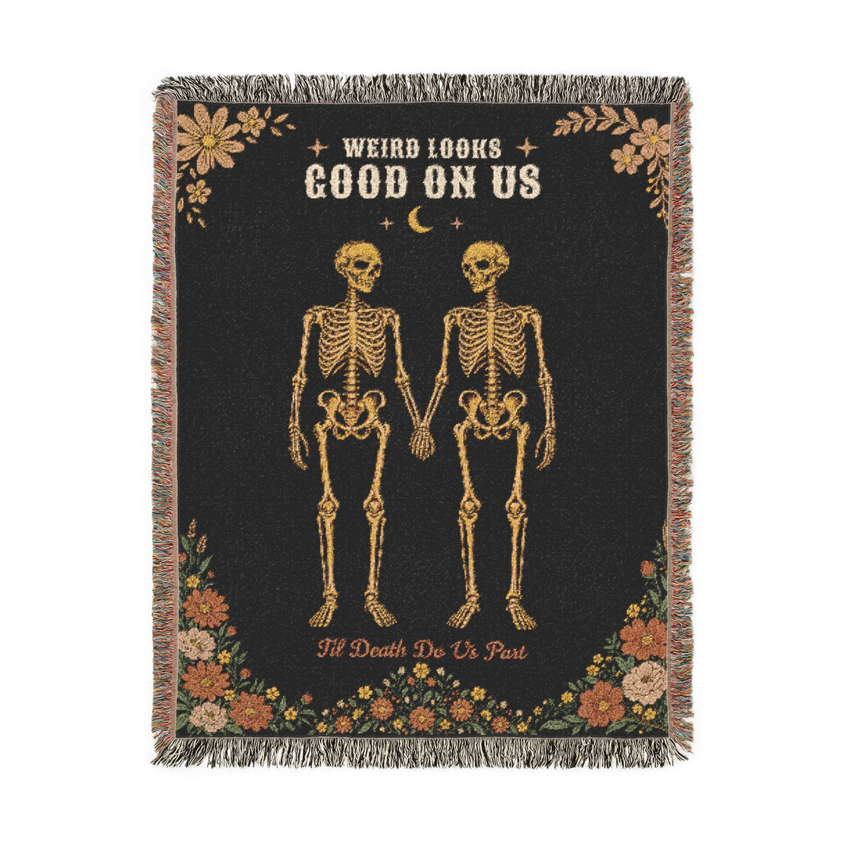 Fringe borders the Black gothic throw blanket in woven cotton, laid flat on white with two skeletons holding hands and wildflowers.