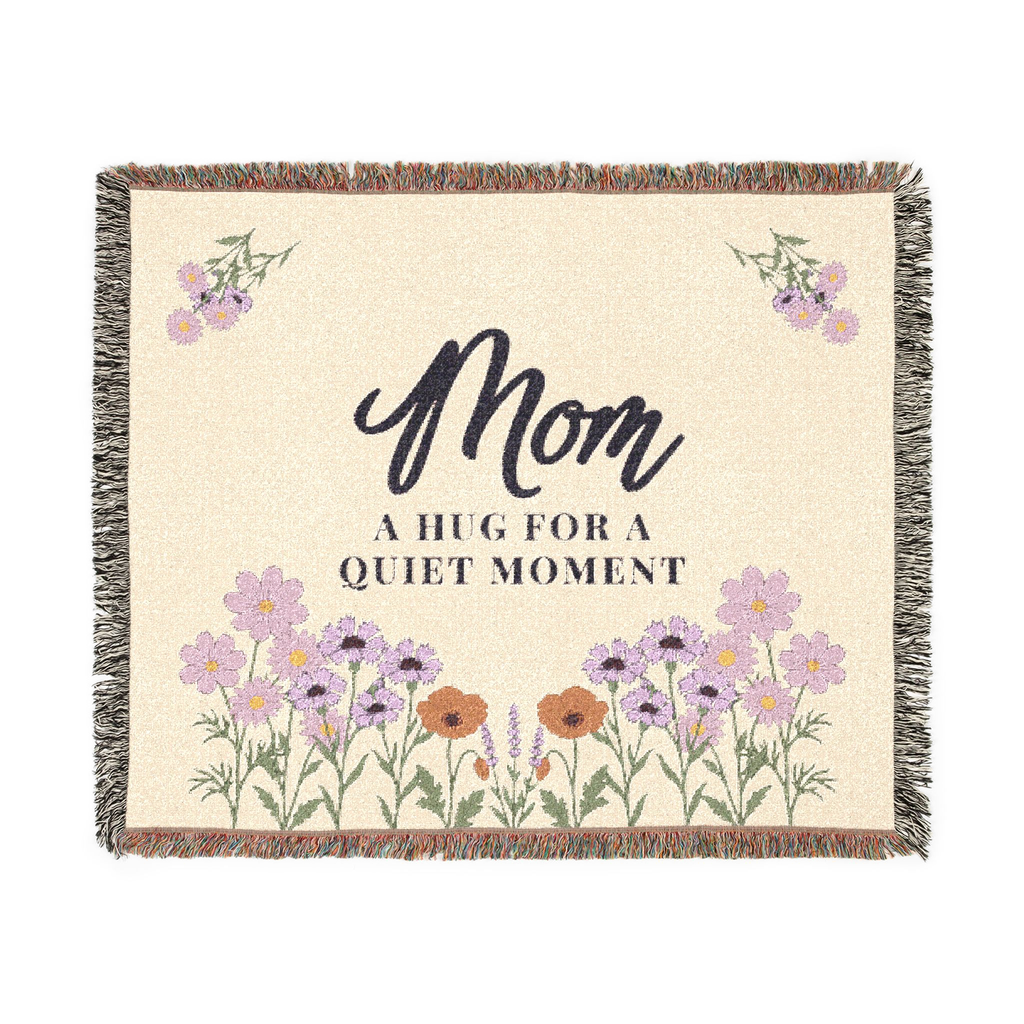 Cream mom throw blanket in woven cotton, 60 x 50 inches, lies flat on white with soft lilac wildflowers, green stems and fringe.