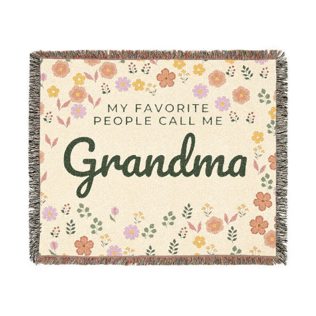 Cream floral throw blanket in woven cotton lies flat on white, with "MY FAVORITE PEOPLE CALL ME Grandma", little flowers and leaves, and fringe on all sides.