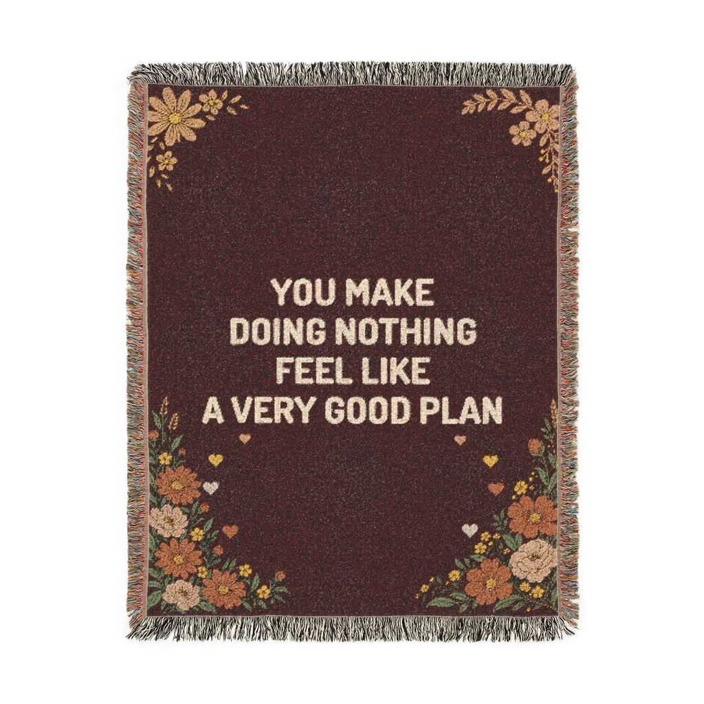Laid flat on white, a fringed Wine woven cotton blanket reads "You make doing nothing feel like a very good plan" with wildflowers and small hearts.
