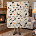 Beside a lit stone fireplace, a man holds up a 50 x 60 inch Cream cat sherpa blanket, showing cartoon cats on its fleece front.