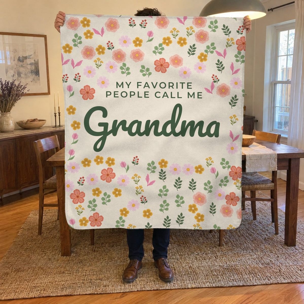 A man holds up a 50 x 60 inch Cream sherpa fleece blanket in a dining room with a wooden table, chairs and a pendant lamp.